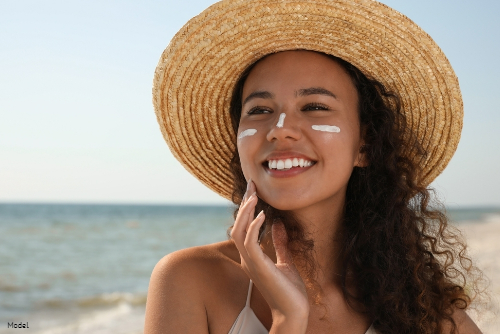 woman smiling, wearing sunscreen on beach